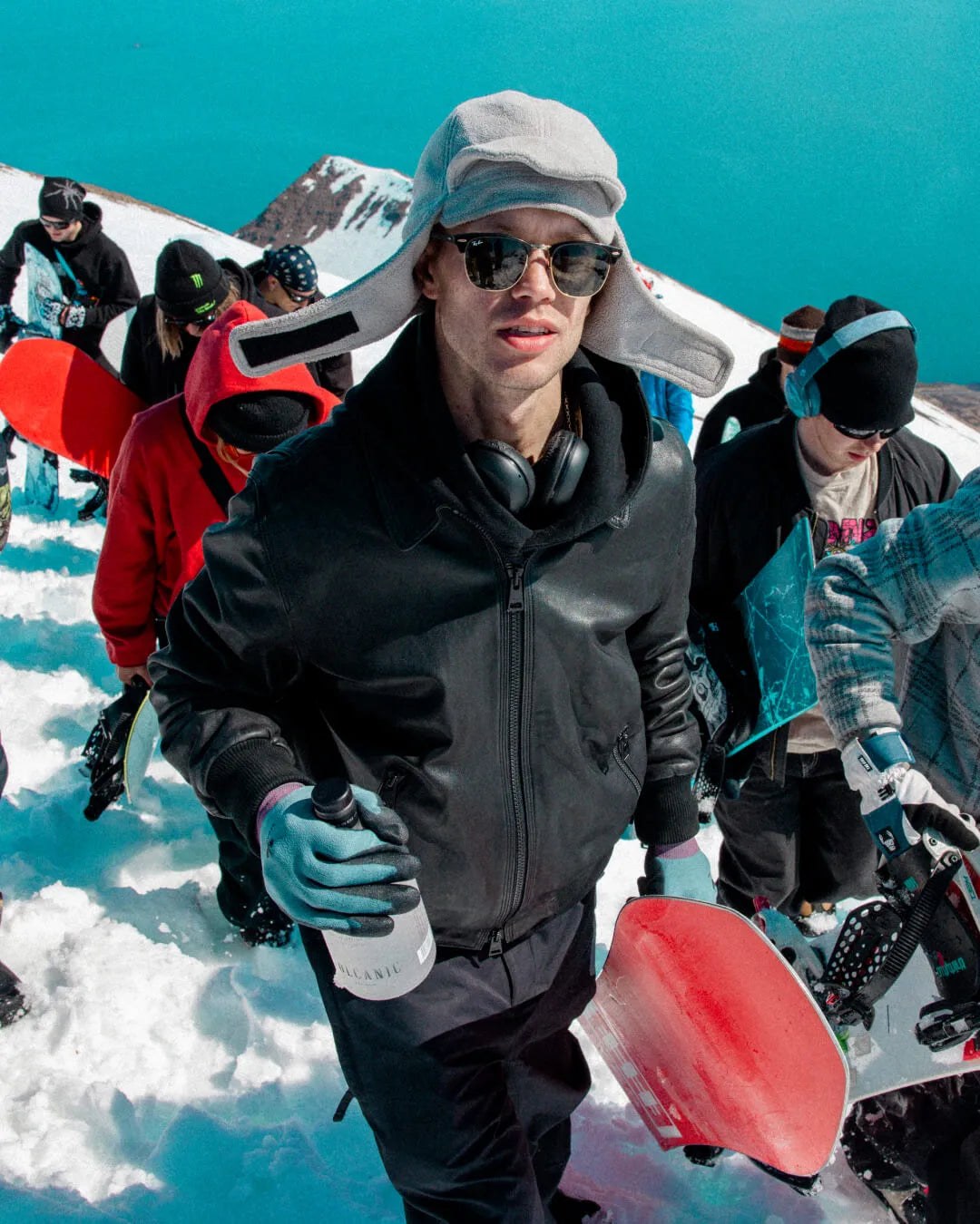 Snowboardere med brett på vei opp i fjellet