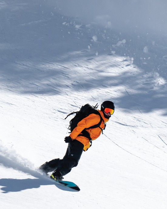 Splitboarder i oransje jakke kjører pudder på Spark R&D-bindinger
