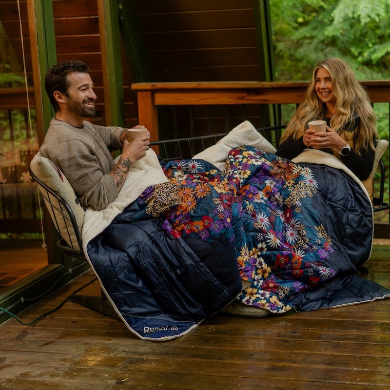 To personer under et Rumpl-pledd på terrassen med kaffe